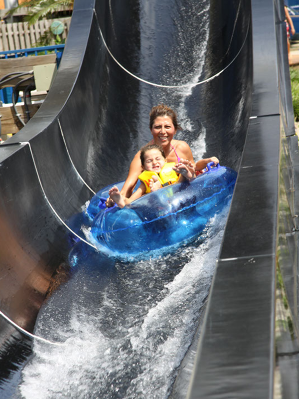 Twist and Splash! This is a pipestyle high-speed tube slide that bends and twists through an open and closed black tube. 

Must be 42″ or taller. Under 48″ must wear lifejacket. Combined weight of riders may not exceed 300 lbs. No single riders.
